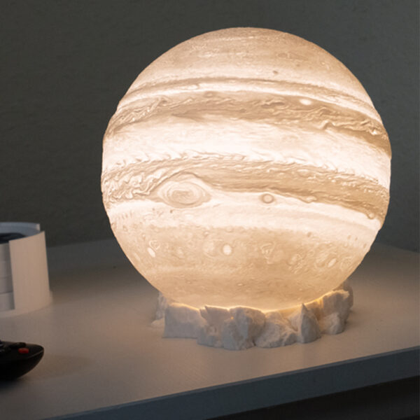 3D printed Jupiter table lamp illuminated on rocky base.