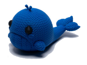 Sad blue knitted whale toy facing forwards the side. He floats!